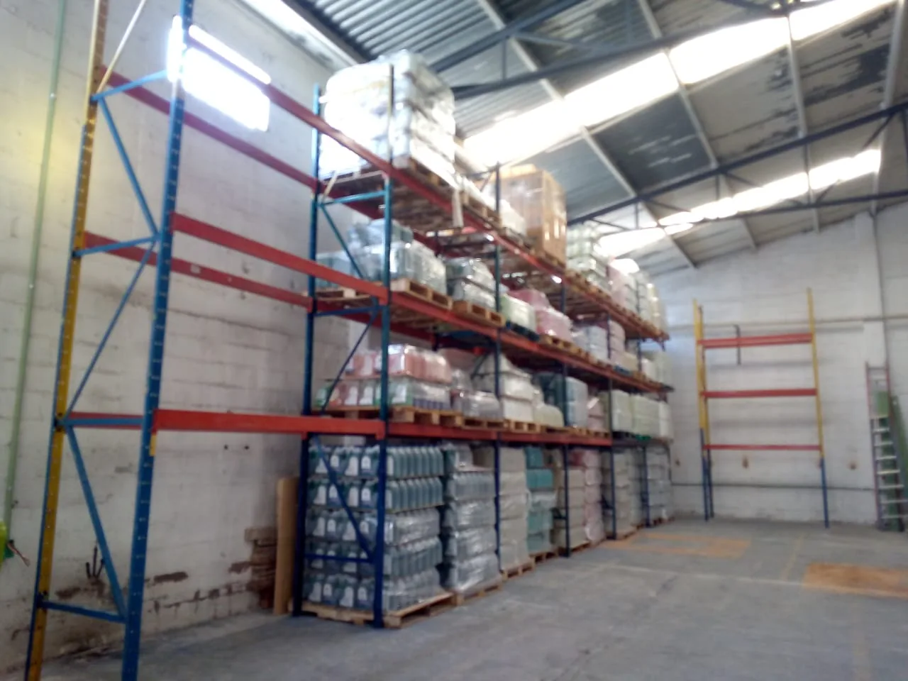 Racks selectivos instalados en un almacén con marcos azules y vigas naranjas